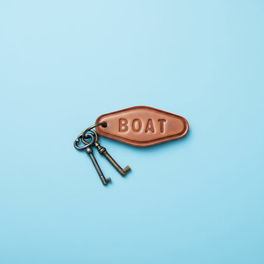 Brown leather keychain with 'BOAT' engraving on a wooden surface