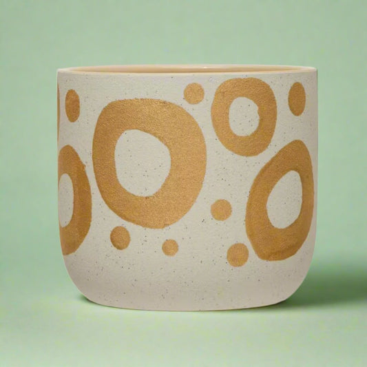 Hand-painted planter with gold spots, filled with greenery, adding a playful yet luxurious touch to a tabletop or windowsill.