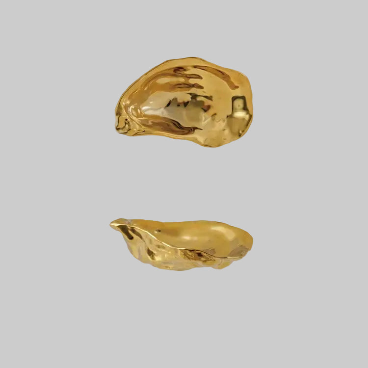 Two gold-colored oyster shells on a white background