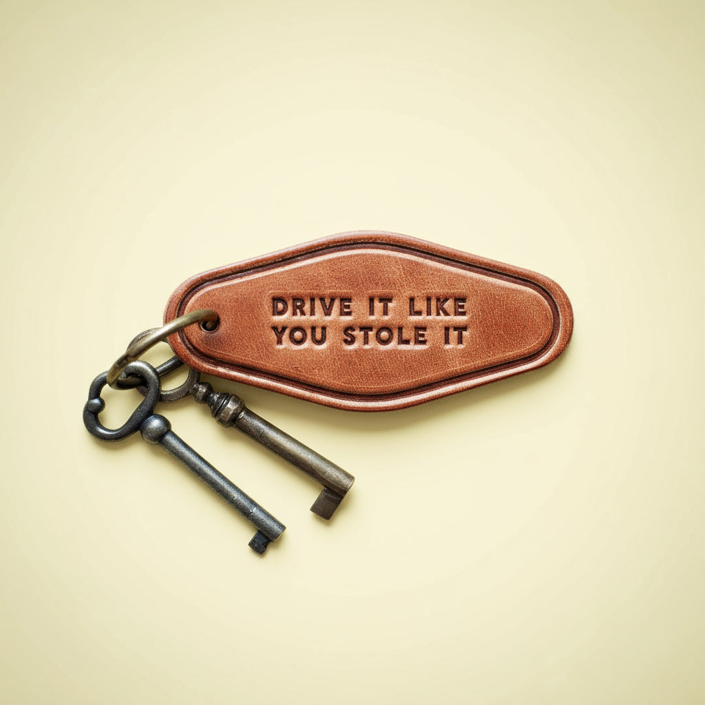 Keychain with 'Drive It Like You Stole It' tag on a wooden surface