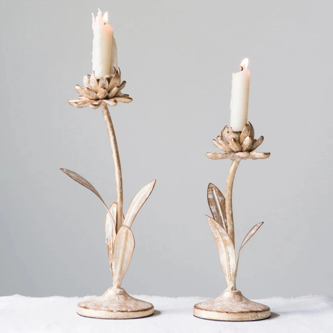 Set of two distressed white and gold flower-shaped metal candle holders for taper candles