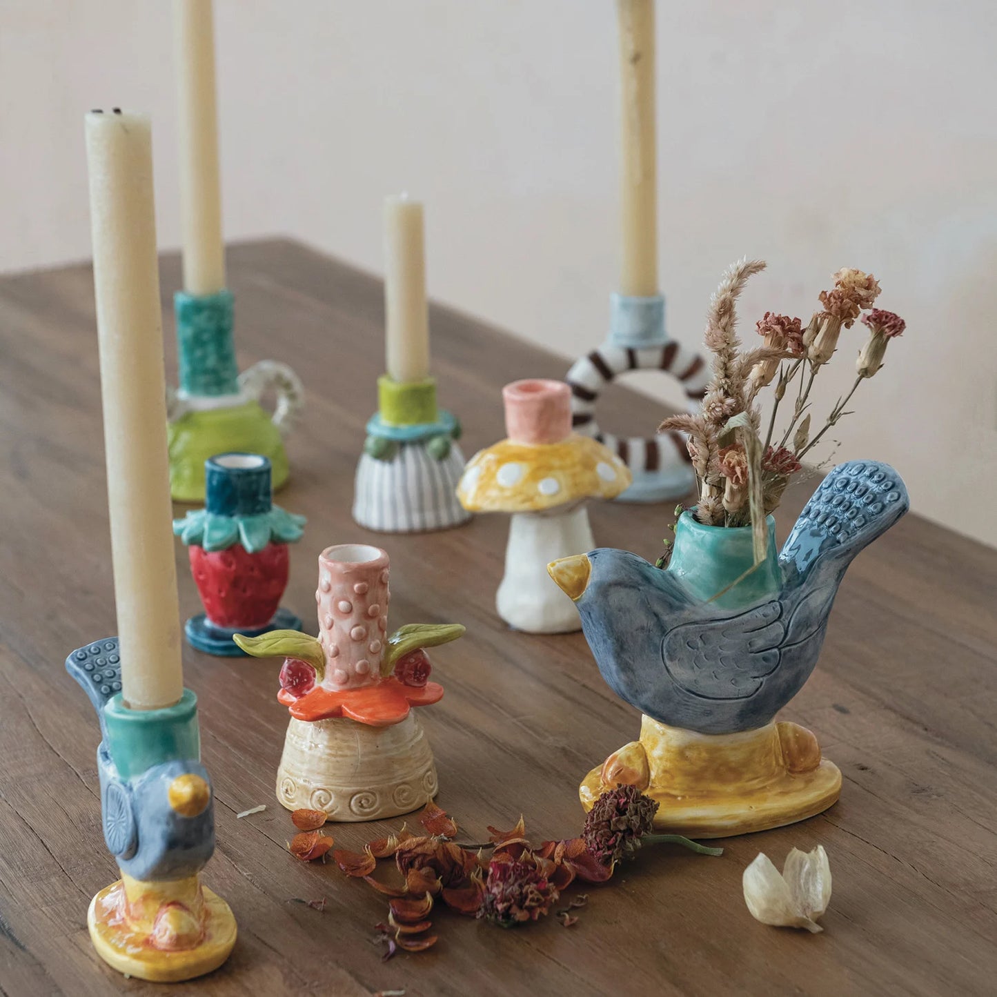 Hand-painted stoneware bird-shaped taper candle holder with navy, teal, and yellow reactive glaze.