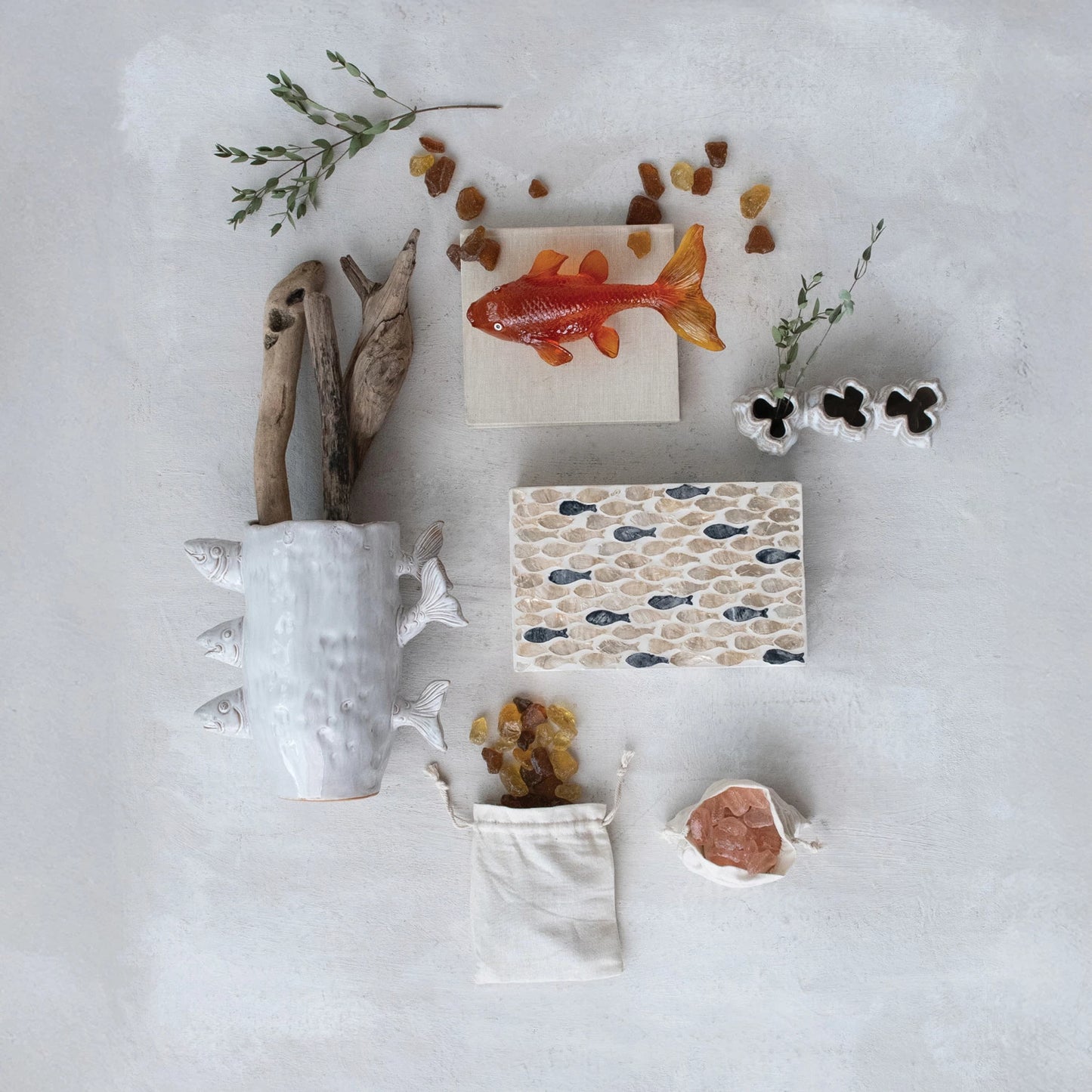Decorative items including a ceramic cup, small plants, and decorative stones on a light gray background