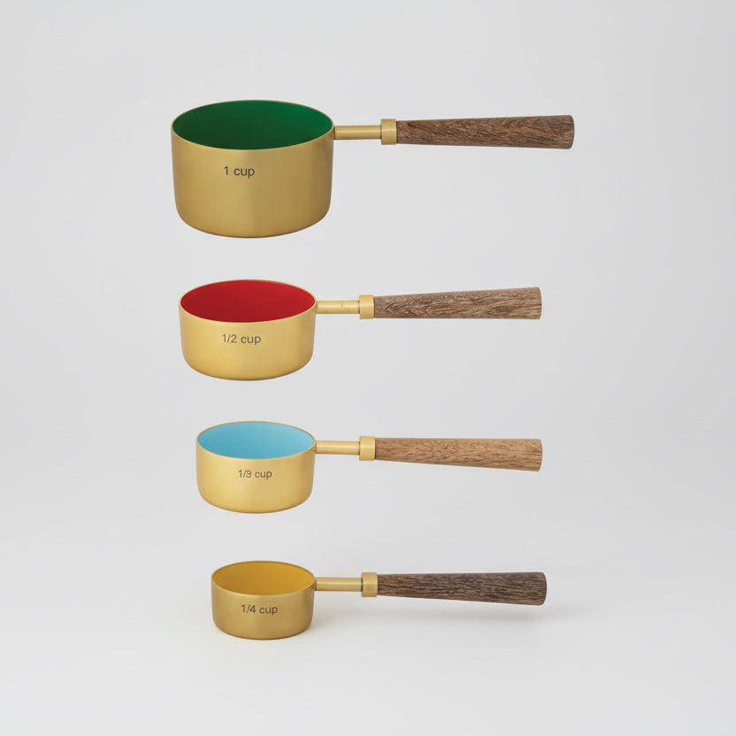 Set of four measuring cups with wooden handles on a white background