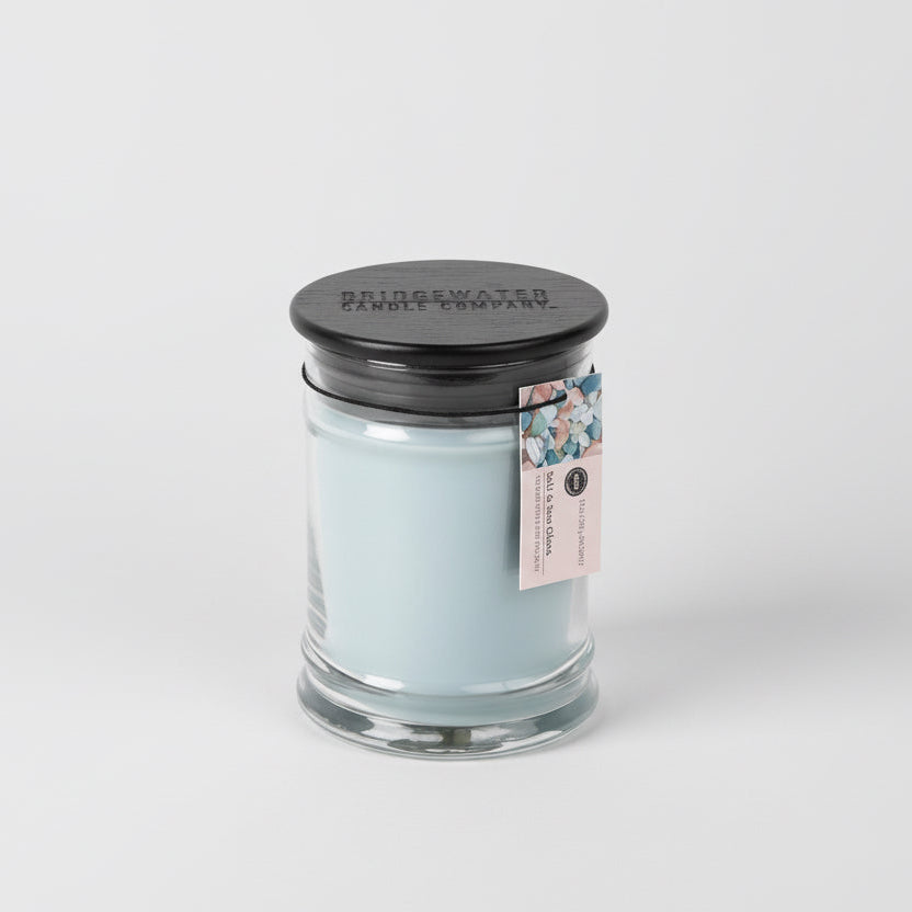 Candle in a glass jar with a black lid on a white background