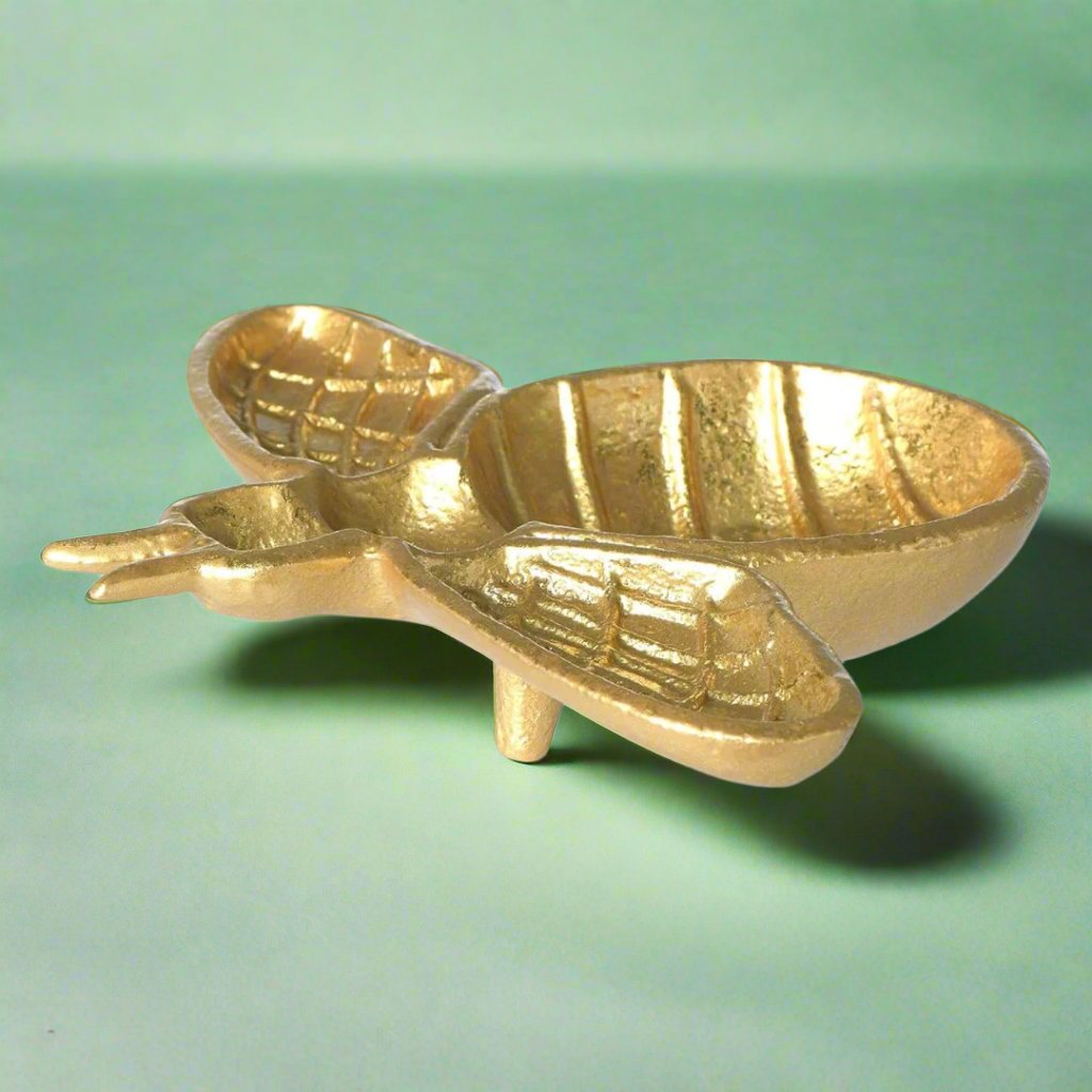 A golden bee-shaped dish, ideal for holding jewelry, soaps, or trinkets, adding a whimsical touch to a bathroom or kitchen counter.