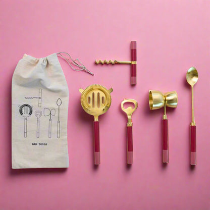 Set_of_five_pink_bar_tools_with_pink_resin_handles_and_a_vintage_brass_finish_including_a_stirring_spoon_strainer_jigger_corkscrew_and_bottle_opener_perfect_for_any_home_bar_setup.