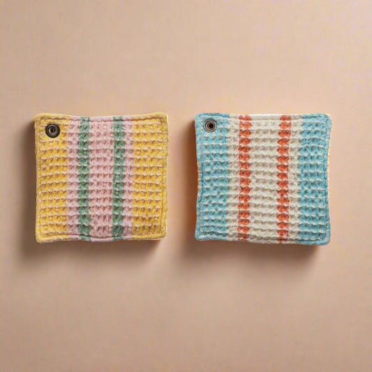 Woven cotton waffle weave pot holders in blue and yellow, designed for safely handling hot dishes while adding a stylish touch to the kitchen.