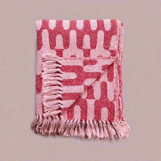 Woventhrowblanketmadefromarecycledcottonblend_featuringastylishpinkpattern_idealforaddingwarmthandsustainablestyletoalivingroomorbedroom.