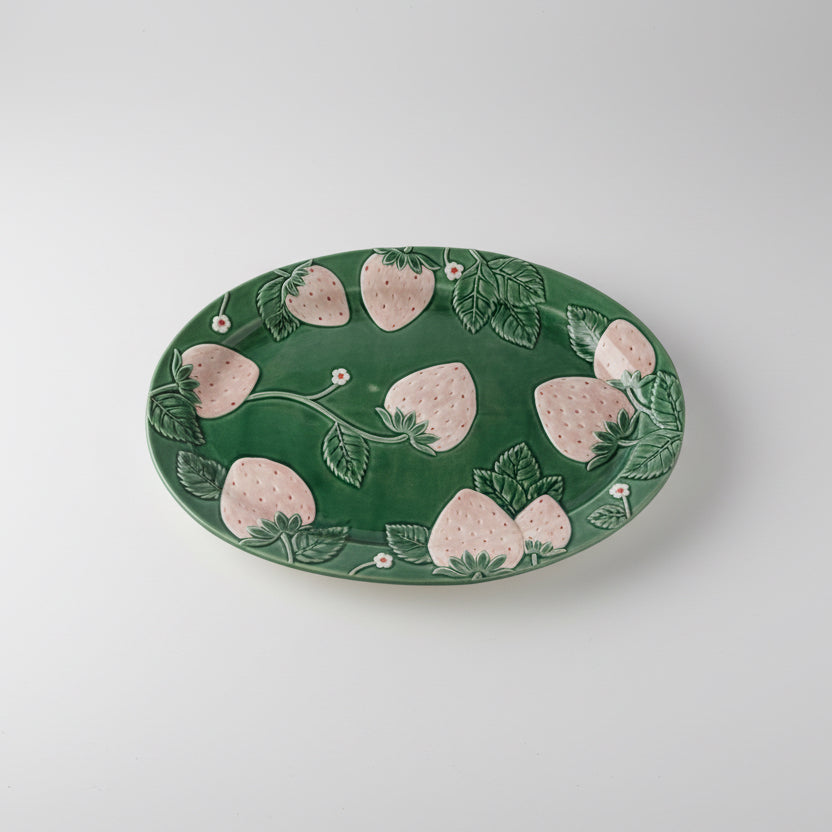 Green ceramic plate with strawberry pattern on a white background