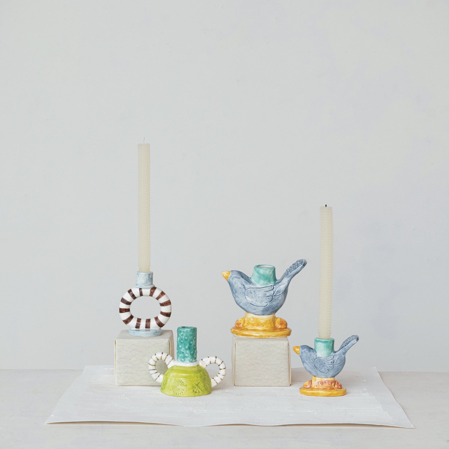 Hand-painted stoneware bird-shaped taper candle holder with navy, teal, and yellow reactive glaze.