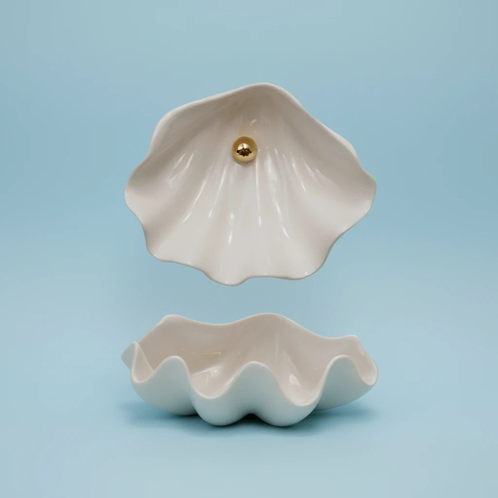 Shell-shaped ceramic container with a gold accent on a white background