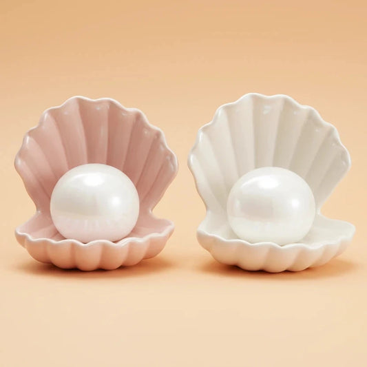 Two shell-shaped containers with pearls inside on a white background