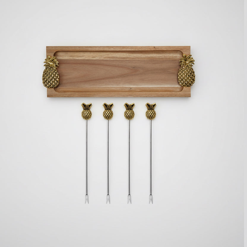 Set of five gold pineapple-shaped cocktail picks with a wooden holder on a white background